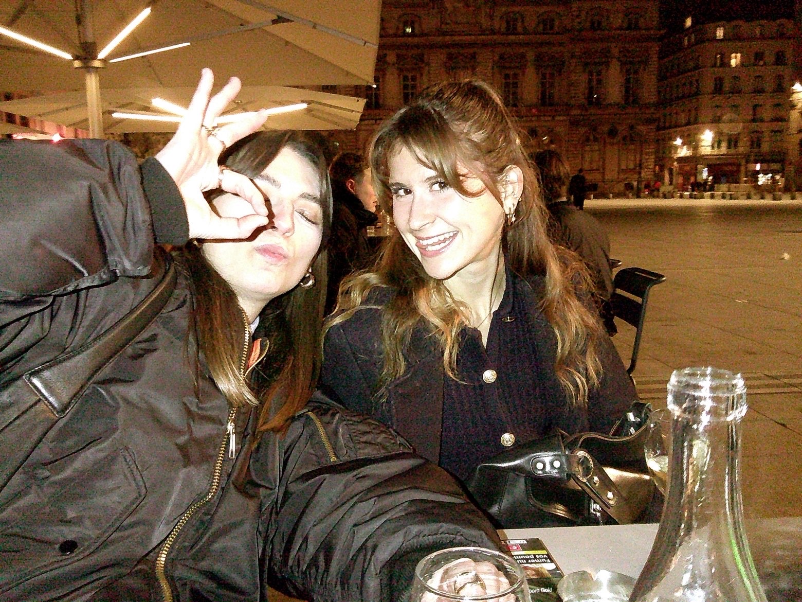 Marie et Judith photographiées au flash à une table de café le soir