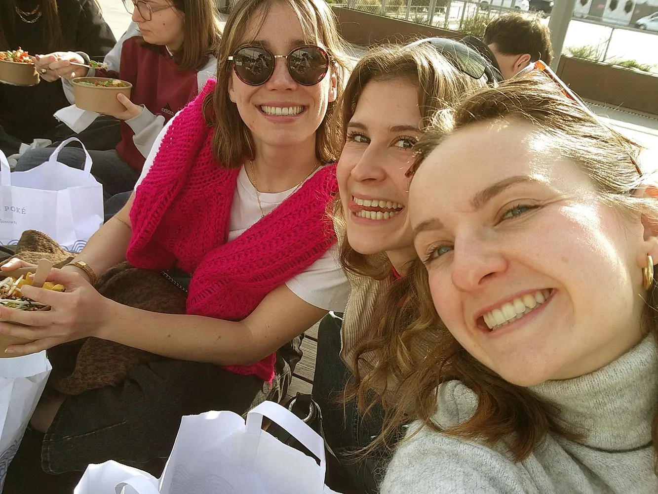 Trois amies sourient à l’objectif pendant un repas